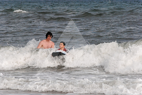 Big brother instructs sibling on surfing.