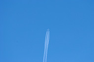 High flying jet against blue sky with contrails.